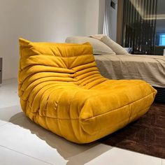 a large yellow chair sitting on top of a white floor next to a bed in a bedroom