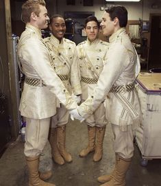 three men in white uniforms are shaking hands with each other while standing next to another man