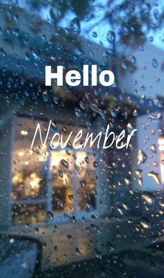 the words hello november are written in front of a window with rain drops on it