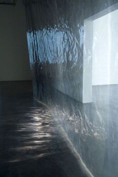 a cat is sitting on the floor in front of a window with water covering it