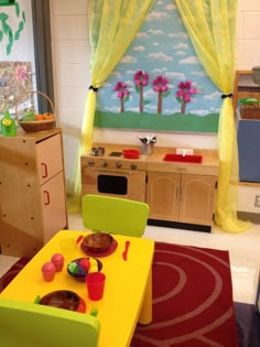 a child's playroom with yellow curtains and green table in front of it