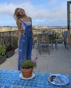 a woman standing on a patio next to a potted plant