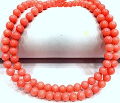 an orange beaded necklace is displayed on a white surface