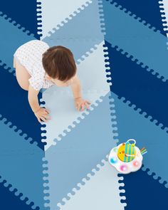 a baby crawling on a blue and white rug