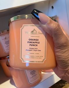 a hand holding a jar of orange pineapple punch