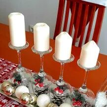 a table with candles and christmas decorations on it, along with two wine glasses filled with white candles