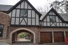 a large brick building with two garages and an arched doorway leading into the yard