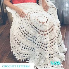 a woman sitting in a chair wearing a white crocheted shawl and red top