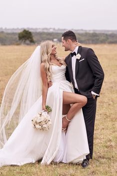 a bride and groom posing for a photo in the middle of a field with grass