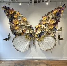 a butterfly made out of flowers and butterflies hanging from the ceiling in front of a white wall