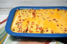 a blue casserole dish filled with cheese and bacon