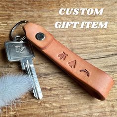 a leather keychain with the words custom gift item engraved on it and a feather