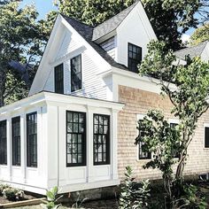 a white house with black windows and shingles