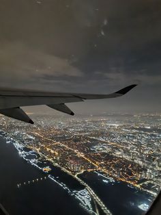 an aerial view of the city lights and water from inside an airplane window at night