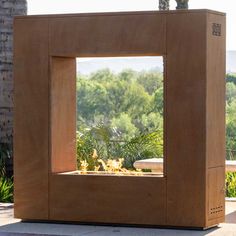 an outdoor fire pit in the middle of a patio with trees and bushes behind it