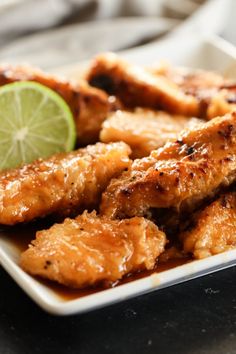 a white plate topped with chicken wings and a lime wedge