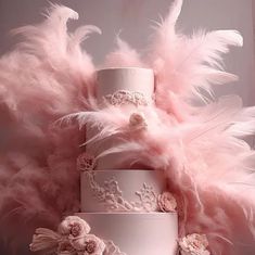 a three tiered wedding cake with pink feathers