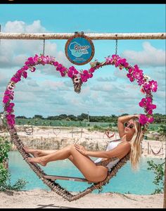 a woman laying in a hammock with flowers on the back and her arms behind her head