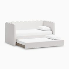 a white bed with scalloped edges and pillows