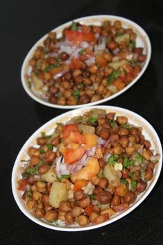 two white plates filled with food sitting on top of a black table next to each other