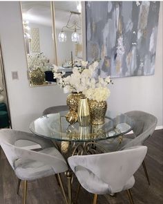 a glass table with chairs around it and flowers in vases on the table top