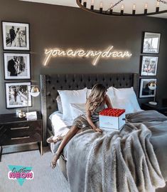 a woman sitting on top of a bed under a neon sign