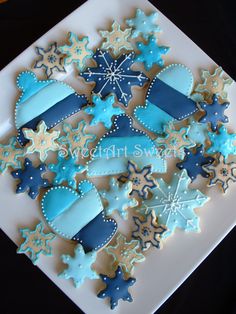 decorated cookies in the shape of snowflakes on a white platter with blue ribbon