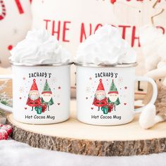 two christmas themed mugs sitting on top of a wooden table