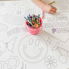 a child's hand is drawing on a happy birthday coloring page with crayons