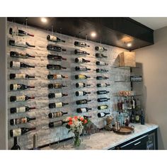 a wine rack with many bottles on it and flowers in vases next to it