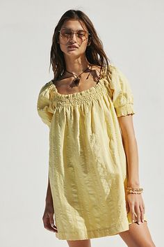 a woman in a yellow dress posing for the camera with her hand on her hip