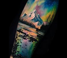 a man's arm with an aurora bore tattoo on it and the mountain in the background