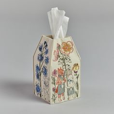 a tissue dispenser with an image of flowers and people on the front