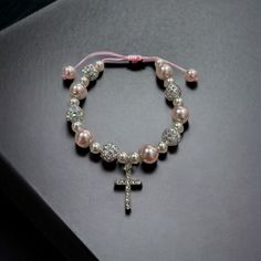 Celebrate a special moment of faith with our handcrafted Beaded Confirmation Bracelet. This elegant piece features a delicate crystal cross, surrounded by beautiful pink and white beads, symbolizing purity and love. Product Details Design: Hand-beaded with pink and white beads, accented by a sparkling crystal cross. Adjustable Fit: Equipped with an adjustable sliding knot, ensuring a perfect fit for any wrist size. Material: High-quality glass beads and a shimmering crystal cross centerpiece. Ve Beaded Cross Jewelry For First Communion, Cross-shaped Beaded Jewelry For First Communion, Adjustable Cross Rosary Bracelet For First Communion, Adjustable Rosary Bracelet With Round Beads For Baptism, Adjustable 8mm Beads Rosary Bracelet For Baptism, Adjustable Jewelry For First Communion Mother's Day, Adjustable Jewelry For Mother's Day First Communion, Adjustable Jewelry For First Communion On Mother's Day, Adjustable Jewelry For First Communion And Mother's Day