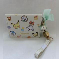 a white purse with pokemon characters on it and a keychain attached to it