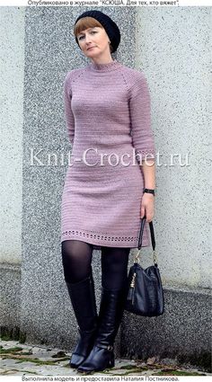 a woman in a purple dress and black boots is holding a handbag while standing next to a wall