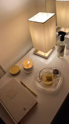 a table topped with two lamps next to a bottle of liquid and a book on top of it