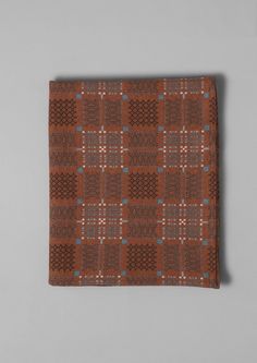 a brown and blue plaid pocket square on a gray background with an orange checkerboard pattern