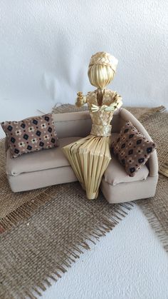 a doll sitting on top of a couch next to pillows