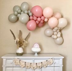 a table topped with balloons and a cake next to a wall mounted balloon art on the wall