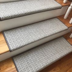 a set of stairs with grey and white patterned carpet on the bottom, next to wooden handrails