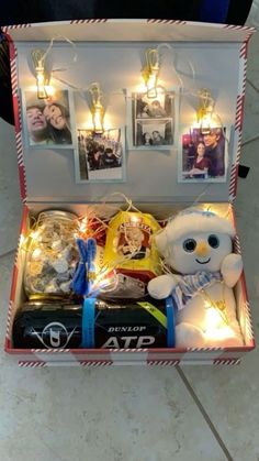 an open box filled with pictures and lights on top of a tile floor next to a stuffed animal