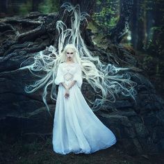 a woman with white hair standing in front of a tree