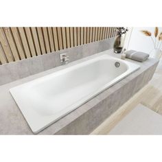 a white bath tub sitting on top of a bathroom counter next to a vase with flowers