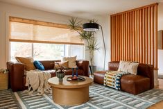 a living room filled with furniture and a large window covered in bamboo blind shades on the windowsill