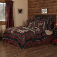 a bed with red and black plaid bedspread in a cabin style bedroom area