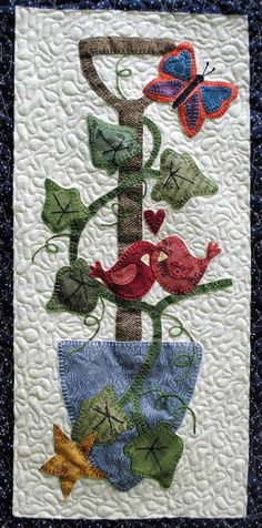 a quilted wall hanging with flowers and butterflies