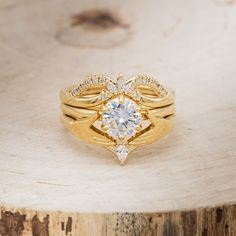 a close up of a gold ring with a diamond on the top and side, sitting on a piece of wood