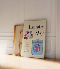 a laundry day sign sitting on top of a wooden floor next to two framed pictures