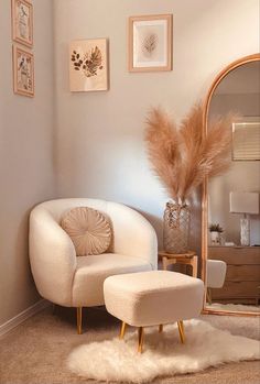 a white chair and ottoman in a room with pictures on the wall above it, along with a large mirror